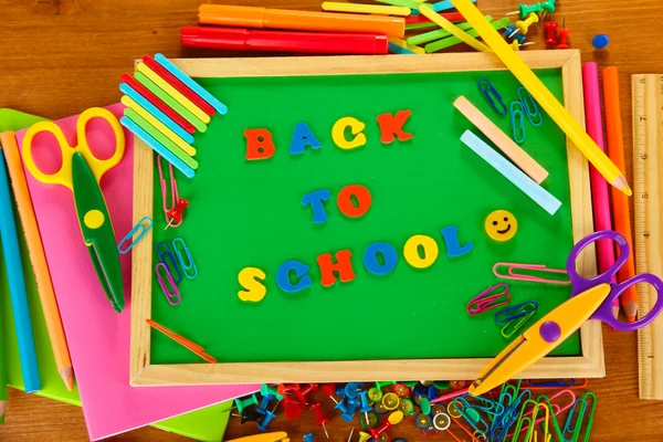 Small chalkboard with school supplies on wooden background. Back to School — Stock Photo, Image