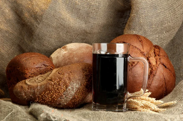 Танкард из кваса и ржаного хлеба с ушами, на фоне мешковины — стоковое фото