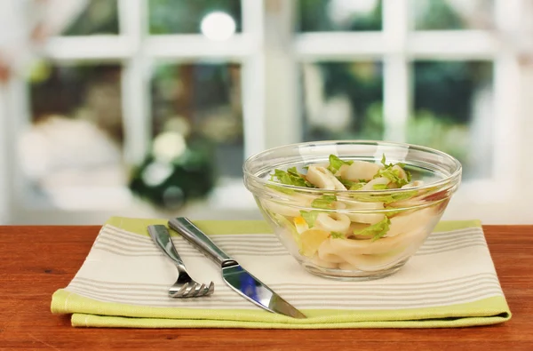 Salade de calmars, citron et laitue dans un bol en verre sur table en bois close-up — Photo