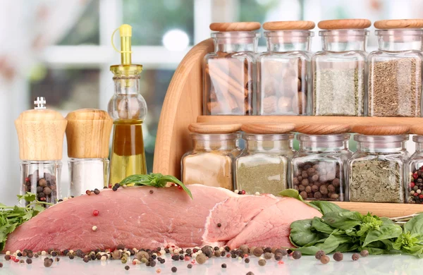 Um grande pedaço de porco marinado com ervas, especiarias e óleo de cozinha na mesa branca no fundo da janela — Fotografia de Stock