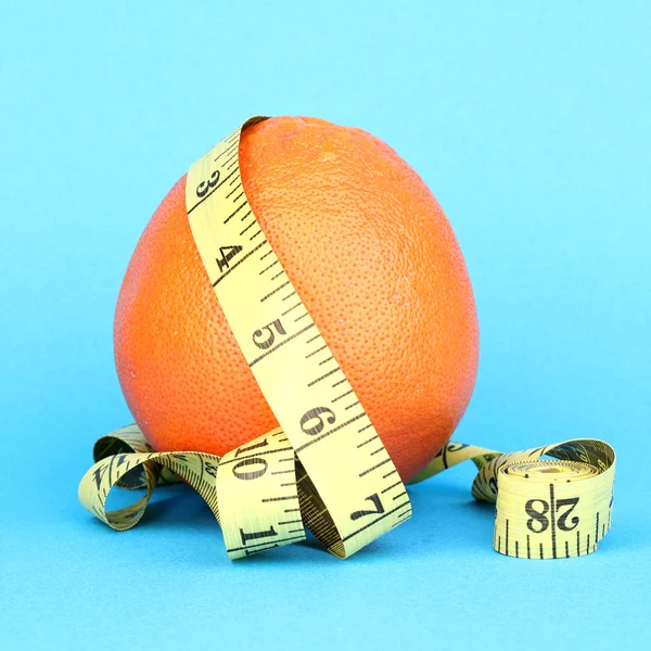 Naranja con cinta métrica sobre fondo azul —  Fotos de Stock