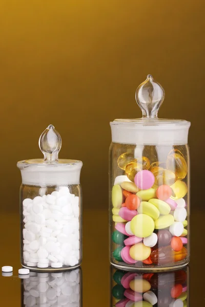 Capsules and pills in receptacles on orange background — Stock Photo, Image