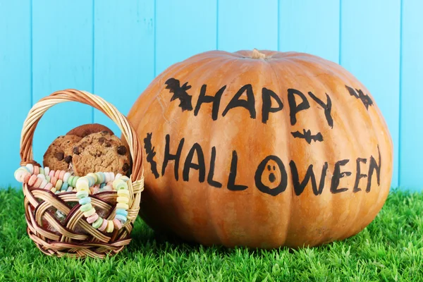 Calabaza de Halloween sobre hierba sobre fondo azul —  Fotos de Stock