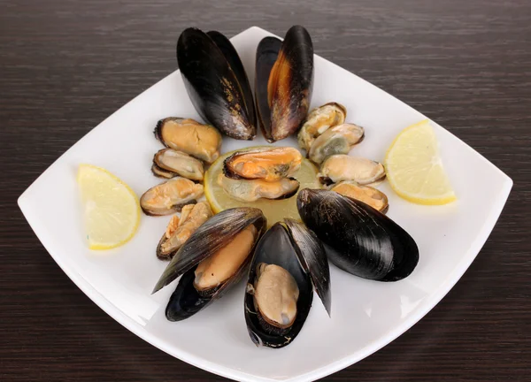 Snack of mussels and lemon on plate on wooden table — Stock Photo, Image