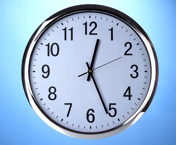 Round office clock on blue background — Stock Photo, Image