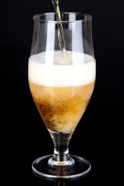 Cerveza vertiendo en vidrio aislado en negro — Foto de Stock