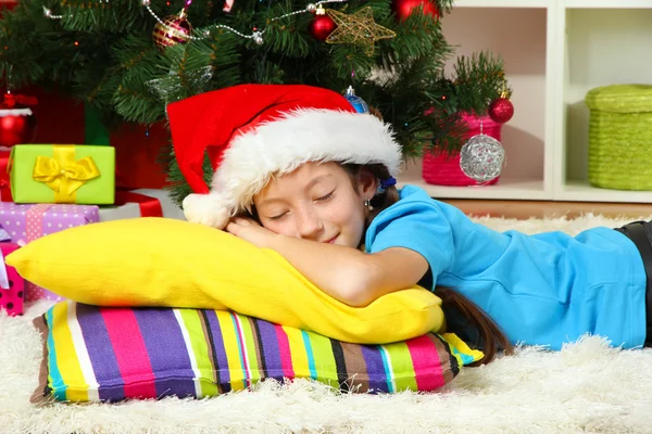 Klein meisje slaapt in de buurt van de kerstboom — Stockfoto