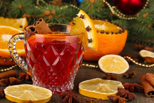 Fragrant mulled wine in glass with spices and oranges around on wooden table — Stock Photo, Image