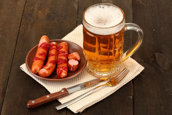 Cerveza y embutidos a la parrilla sobre fondo de madera — Foto de Stock