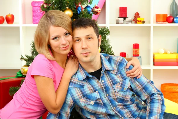 Young happy couple near a Christmas tree at home — Stock Photo, Image