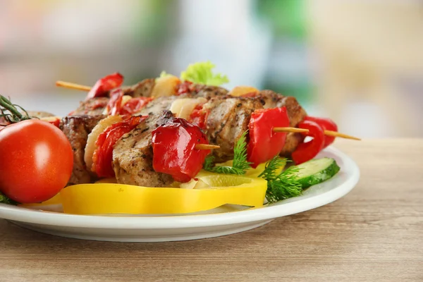 Smaczne grillowane mięso i warzywa na szpikulcu na talerzu, na drewnianym stole — Zdjęcie stockowe