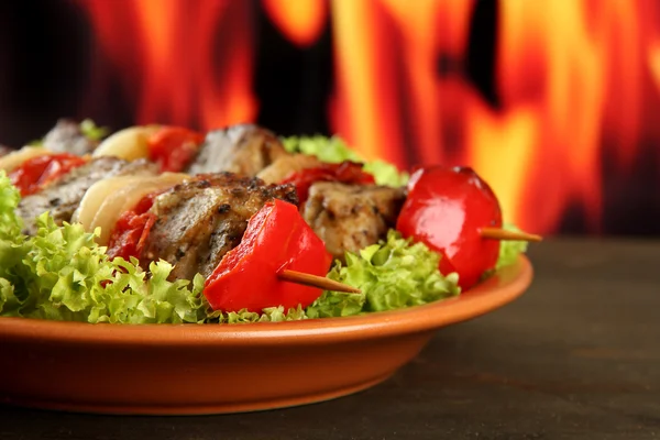 Sabrosa carne a la parrilla y verduras en el plato, sobre fondo de fuego — Foto de Stock