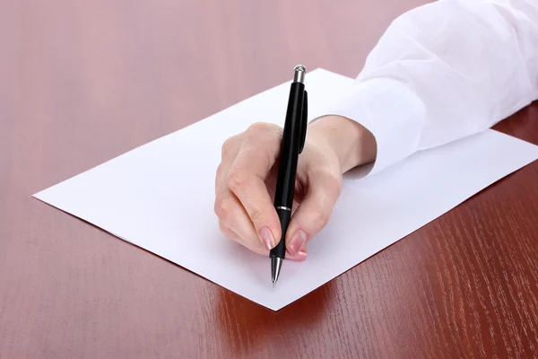 Woman hand writing on paper, on wooden table Royalty Free Stock Photos