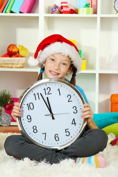 Little girl holding clock near christmas tree Stock Photo