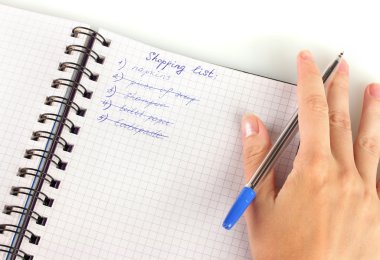 Kadının elinde alışveriş listesi olan bir defter var.