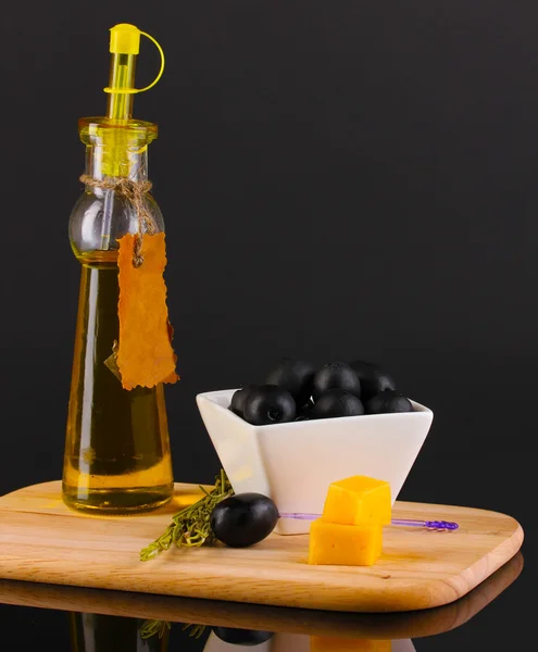 Aceitunas negras en tazón blanco con romero, aceite de oliva y queso a bordo aisladas sobre negro — Foto de Stock