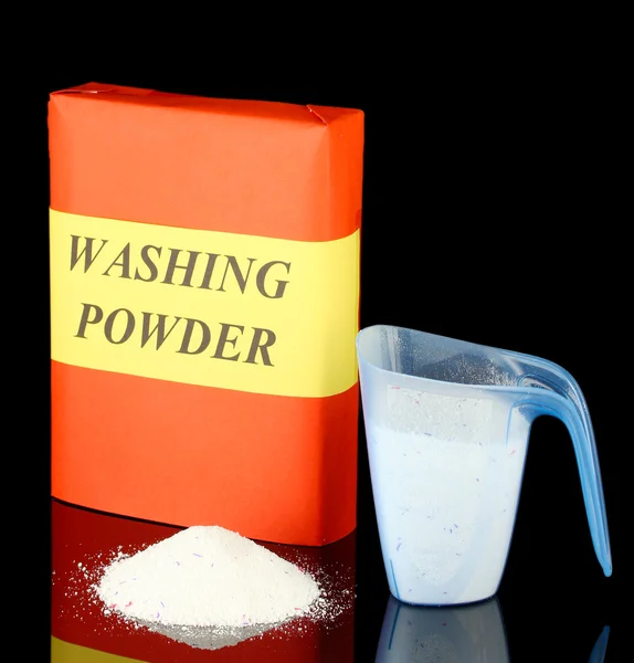 Box of washing powder with blue measuring cup, isolated on black — Stock Photo, Image