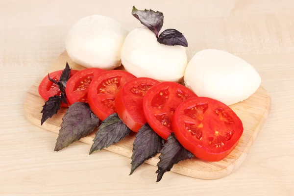 Savoureuse mozzarella aux tomates sur planche à découper sur tapis — Photo