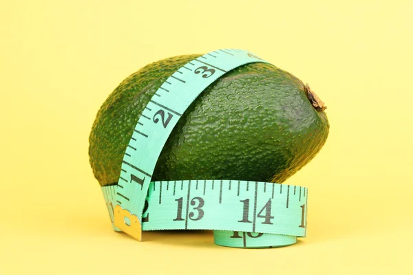 Avocado met meetlint op gele achtergrond — Stockfoto