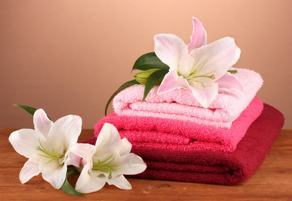 Pilha de toalhas com lírio rosa em um fundo marrom — Fotografia de Stock
