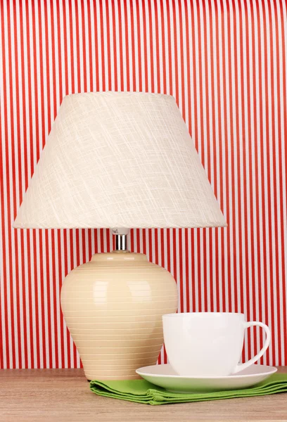 Lampada da tavolo e tazza su sfondo a strisce — Foto Stock