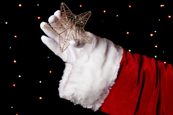 Santa Claus mano celebración de la estrella de Navidad sobre fondo brillante — Foto de Stock