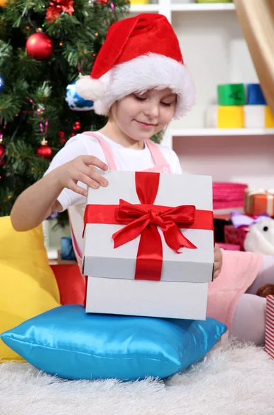 Una bambina apre un regalo in una stanza decorata a festa — Foto Stock