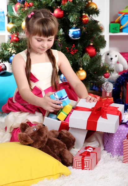 Menina bonita é um presente feliz no quarto festivamente decorado — Fotografia de Stock