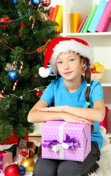 Klein meisje houden de doos van de gift in de buurt van de kerstboom — Stockfoto