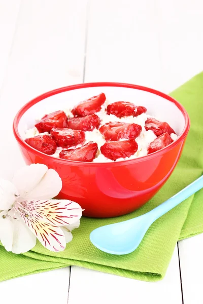 Cottage cheese in red bowl with sliced strawberries on white wooden table — Stock Photo, Image