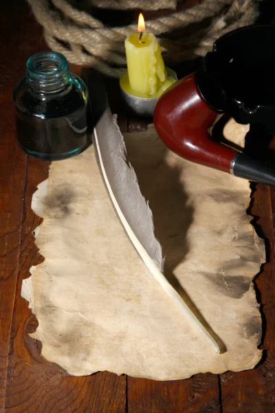 Papel viejo con pluma de tinta cerca de la vela de iluminación en la mesa de madera —  Fotos de Stock