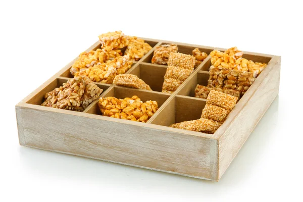 Вкусные сладости (козинаки) в деревянном ящике, изолированном на белом — стоковое фото