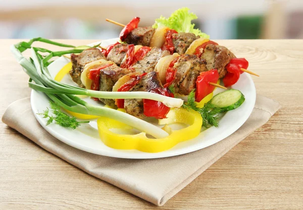 Tasty grilled meat and vegetables on skewer on plate, on wooden table — Stock Photo, Image