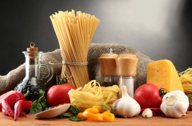 Pasta spaghetti, vegetables and spices, on wooden table, on grey background clipart