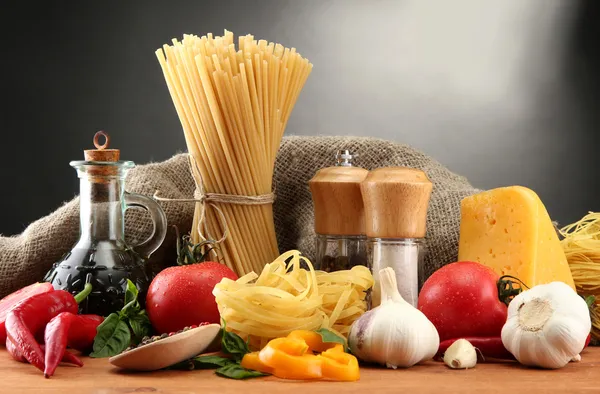 Nudelspaghetti, Gemüse und Gewürze, auf Holztisch, auf grauem Hintergrund — Stockfoto