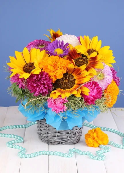 Piękny bukiet kwiatów jasny na drewnianym stole na niebieskim tle — Zdjęcie stockowe