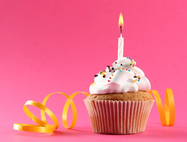 Cupcake de aniversário saboroso com vela, no fundo rosa — Fotografia de Stock