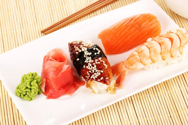 Délicieux sushi servi sur assiette sur tapis de bambou — Photo