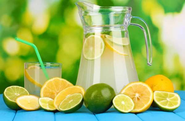 Citrus saft i kannan och glas av citrus runt på naturliga träbord på blå bakgrund — Stockfoto