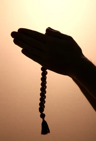 Mani maschili con rosario, su sfondo marrone — Foto Stock