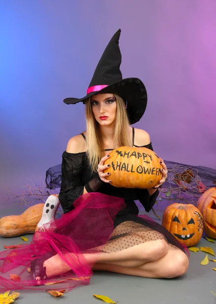 Halloween witch holding pumpkin on color background — Stock Photo, Image