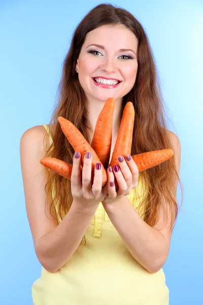 Mooie vrouw met wortel op blauwe achtergrond — Stockfoto