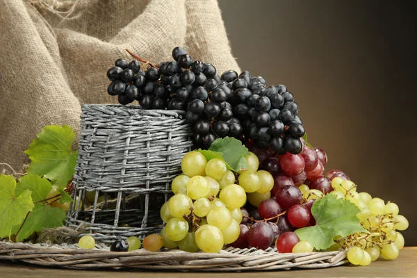 Assortimento di uve dolci mature in cesto, su fondo marrone — Foto Stock