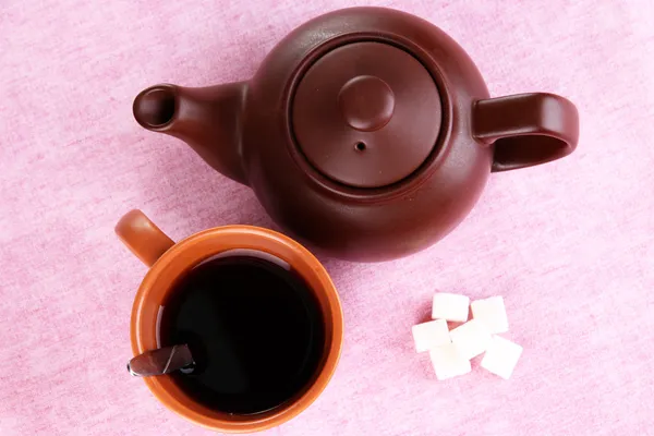 Top view of cup of tea and teapot on pink tablecloths — Stock Photo, Image