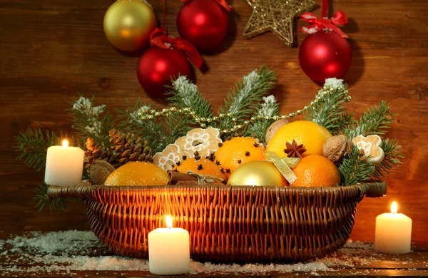 Composição de natal em cesta com laranjas e abeto, sobre fundo de madeira — Fotografia de Stock