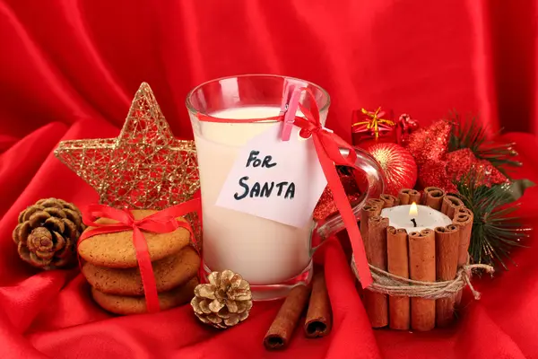 Cookies for Santa: Conceptual image of ginger cookies, milk and christmas decoration on red background — Stock Photo, Image