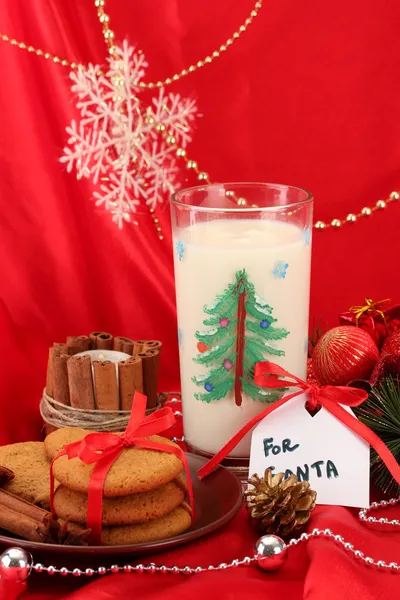 Cookies for Santa: Conceptual image of ginger cookies, milk and christmas decoration on red background — Stock Photo, Image