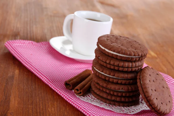 Biscotti al cioccolato con strato cremoso e tazza di caffè sul tavolo di legno primo piano — Foto Stock