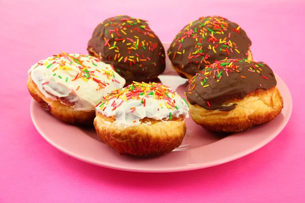 Tasty donuts on color plate on color background — Stock Photo, Image