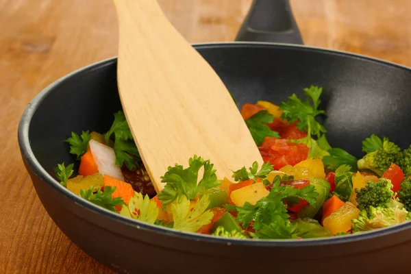 Skivade färska grönsaker i pannan på träbord — Stockfoto